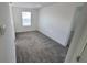 Well-lit bedroom featuring soft gray carpeting, white walls, and natural light from a window at 443 Cool Summer Ln, Davenport, FL 33837