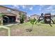 Backyard featuring a screened-in patio, playset, and lush landscaping at 4447 Maple Chase Trl, Kissimmee, FL 34758