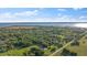 Expansive aerial shot of land with dense trees, scattered houses, and a view of a lake in the distance at 4505 Kissimmee Park Rd, St Cloud, FL 34772