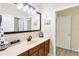 This bathroom features wood-look floors, a wood vanity with a black faucet, and a large, well-lit mirror at 4720 Doral Pointe Dr, Kissimmee, FL 34758
