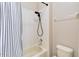 This bathroom features white subway tile, a black shower head, and a modern black and white striped shower curtain at 4720 Doral Pointe Dr, Kissimmee, FL 34758