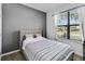 Bright bedroom featuring wood floors, a gray accent wall, and a window with views of the well-maintained front yard at 4720 Doral Pointe Dr, Kissimmee, FL 34758