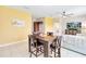 Cozy dining room with hardwood table, four chairs and yellow accent wall adjacent to living room at 4720 Doral Pointe Dr, Kissimmee, FL 34758