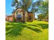 Lawn view of a two-story tan home with a palm tree and manicured grass at 4720 Doral Pointe Dr, Kissimmee, FL 34758
