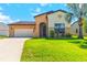 Charming home featuring an arched entry, two-car garage, and a well-manicured front lawn with a palm tree at 4720 Doral Pointe Dr, Kissimmee, FL 34758