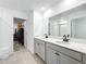 Modern bathroom featuring double vanity with gray cabinets, quartz countertop, and a walk-in closet at 5712 Bristleleaf Ct, Leesburg, FL 34748