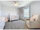 Charming Bedroom features a white crib, comfortable chair, and natural light from the window at 5712 Bristleleaf Ct, Leesburg, FL 34748