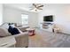 Cozy living room featuring a plush gray sectional, ceiling fan, and an entertainment center with mounted television at 5712 Bristleleaf Ct, Leesburg, FL 34748