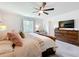 Serene primary bedroom features a large bed, a wooden dresser, and a cozy armchair by the window at 5712 Bristleleaf Ct, Leesburg, FL 34748