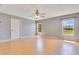 Bright bedroom with hardwood floors, gray walls, a ceiling fan, and large windows overlooking a lush outdoor view at 6555 Bay Tree Ct, St Cloud, FL 34771