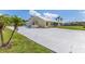 Exterior side view of the property showcasing a concrete driveway, manicured lawn, and mature palm trees at 6555 Bay Tree Ct, St Cloud, FL 34771