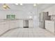 Open kitchen with stainless appliances, tile floors, white cabinets, and view into the living space at 6555 Bay Tree Ct, St Cloud, FL 34771