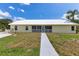 Rear view of the home featuring a screened porch, well-kept lawn, and concrete walkway at 6555 Bay Tree Ct, St Cloud, FL 34771