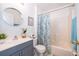 Bathroom featuring a shower-tub combo with decorative curtain, a vanity with storage, and a round mirror at 812 Adour Dr, Kissimmee, FL 34759