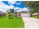 Charming single-story home with a manicured lawn, an attached two-car garage, and mature trees at 812 Adour Dr, Kissimmee, FL 34759