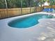 Sparkling in-ground pool surrounded by a screened enclosure and patio chairs at 1006 Soaring Eagle Ln, Kissimmee, FL 34746