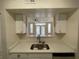 Modern kitchen featuring a double sink, white cabinets, and a pass-through window to the living area at 1020 Siena Park W Blvd # 304, Kissimmee, FL 34747