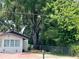Home exterior featuring lush green trees, fencing, and white facade at 1101 28Th Nw St, Winter Haven, FL 33881
