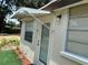 Back entrance featuring a storm door, exterior lighting, and green turf, providing convenient access to the home at 1101 28Th Nw St, Winter Haven, FL 33881