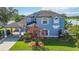 Stunning two-story lakefront home with a vibrant blue exterior, lush landscaping, and covered side-entry garage at 12134 Shadowbrook Ln, Orlando, FL 32828