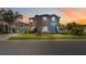 Beautiful two-story home featuring a porte-cochere, lush landscaping, and classic architectural details at sunset at 12134 Shadowbrook Ln, Orlando, FL 32828