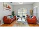 Bright living room features hardwood floors, a modern chandelier, and a wall painting above a red sofa at 12134 Shadowbrook Ln, Orlando, FL 32828