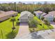 Aerial view of a well-maintained single-story home with a brick driveway, lush lawn, and mature trees at 1703 Encinitas Way, Kissimmee, FL 34759