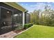 Backyard featuring screened lanai, landscaped lawn, and view of the surrounding wooded area at 1703 Encinitas Way, Kissimmee, FL 34759