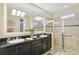 Modern bathroom featuring double sinks, granite countertops, a large mirror, and a glass-enclosed shower at 1703 Encinitas Way, Kissimmee, FL 34759