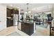 Modern kitchen with a center island, stainless steel appliances, and dark wood cabinetry, opening to the dining and living area at 1703 Encinitas Way, Kissimmee, FL 34759