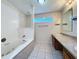 Tiled bathroom featuring a soaking tub, vanity with double sinks, and a large window for natural light at 2409 E Magnolia St, Lakeland, FL 33801
