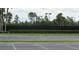 Well maintained tennis court with a black fence surrounded by lush landscaping and parking area at 2673 Rainbow Springs Ln, Orlando, FL 32828