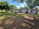 Rear exterior view of property with mature trees, lawn, and patio area at 2704 Sample St, Kissimmee, FL 34744