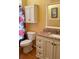 A bathroom with a granite countertop, cream colored vanity and storage, toilet, and shower with floral curtain at 2779 Theresa Dr, Kissimmee, FL 34744