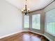 Bright dining room featuring hardwood flooring and a stylish chandelier, illuminated by natural light from adjacent windows at 30 Lake Diamond Ave, Ocala, FL 34472
