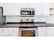 Updated kitchen features white cabinetry, sleek stainless steel appliances, and sophisticated black countertops at 30 Lake Diamond Ave, Ocala, FL 34472