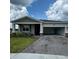 Inviting single-Gathering home features a brick-paved driveway, two-car garage, and charming front porch at 4053 Redbridge Loop, Davenport, FL 33837