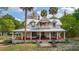Charming two-story home featuring a large front porch with beautiful architectural details and mature trees at 525 W Blue Springs Ave, Orange City, FL 32763