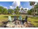 Spacious yard featuring a fire pit with Adirondack chairs with lush green grass and mature trees at 525 W Blue Springs Ave, Orange City, FL 32763