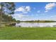 View of the backyard, featuring a serene pond surrounded by lush green grass and mature trees at 561 Tapatio Ln, Kissimmee, FL 34759