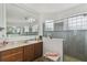 Bathroom with dual sinks, granite counters, wood cabinets, and a seamless glass shower at 561 Tapatio Ln, Kissimmee, FL 34759