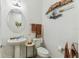 This powder room features a pedestal sink, decorative mirror, stylish fixtures, and a unique wall sculpture at 561 Tapatio Ln, Kissimmee, FL 34759