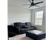 Cozy living room with a comfortable reclining sofa, black ottoman, and a ceiling fan for added comfort at 5725 Iron Brand Rd, St Cloud, FL 34771