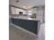 Bright kitchen featuring white cabinets, a breakfast bar with blue paneling, and modern backsplash with sleek appliances at 6489 Creation St, St Cloud, FL 34771