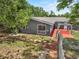 Quaint backyard features stepping stones, garden beds, mature trees, a grey house, and a red deck at 710 Carlton Ave, Lake Wales, FL 33853