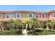 Inviting townhome featuring colorful exterior, white shutters, red tile roof, and beautiful landscaping with palm trees at 8517 Bay Lilly Loop, Kissimmee, FL 34747
