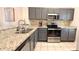 Well-lit kitchen with gray cabinets, granite countertops, stainless steel appliances, and tiled flooring at 8517 Bay Lilly Loop, Kissimmee, FL 34747