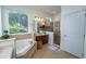 Bathroom with double sinks, a jacuzzi tub, and cherry wood cabinets at 8835 Abbey Leaf Ln, Orlando, FL 32827