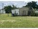 Backyard view of a shed and parts of a dilapidated structure on an expansive lawn at 127 Alabama Ave, St Cloud, FL 34769