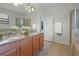 Well-lit bathroom boasts double sinks, granite counters, and a glass-enclosed shower at 1394 Palmetto Dunes St, Champions Gate, FL 33896